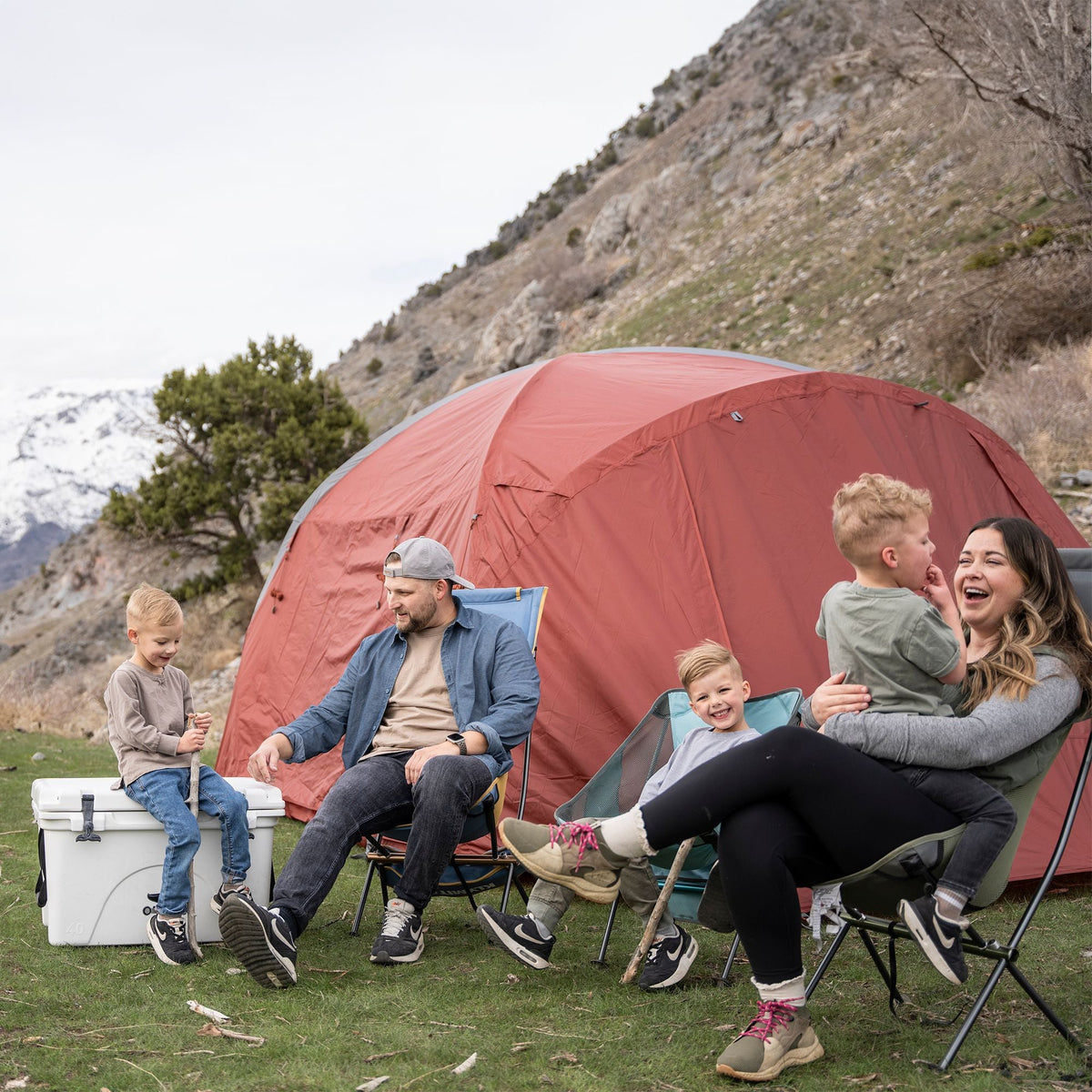 Family in camp chairs in front of the Klymit Cross Canyon 6 Tent